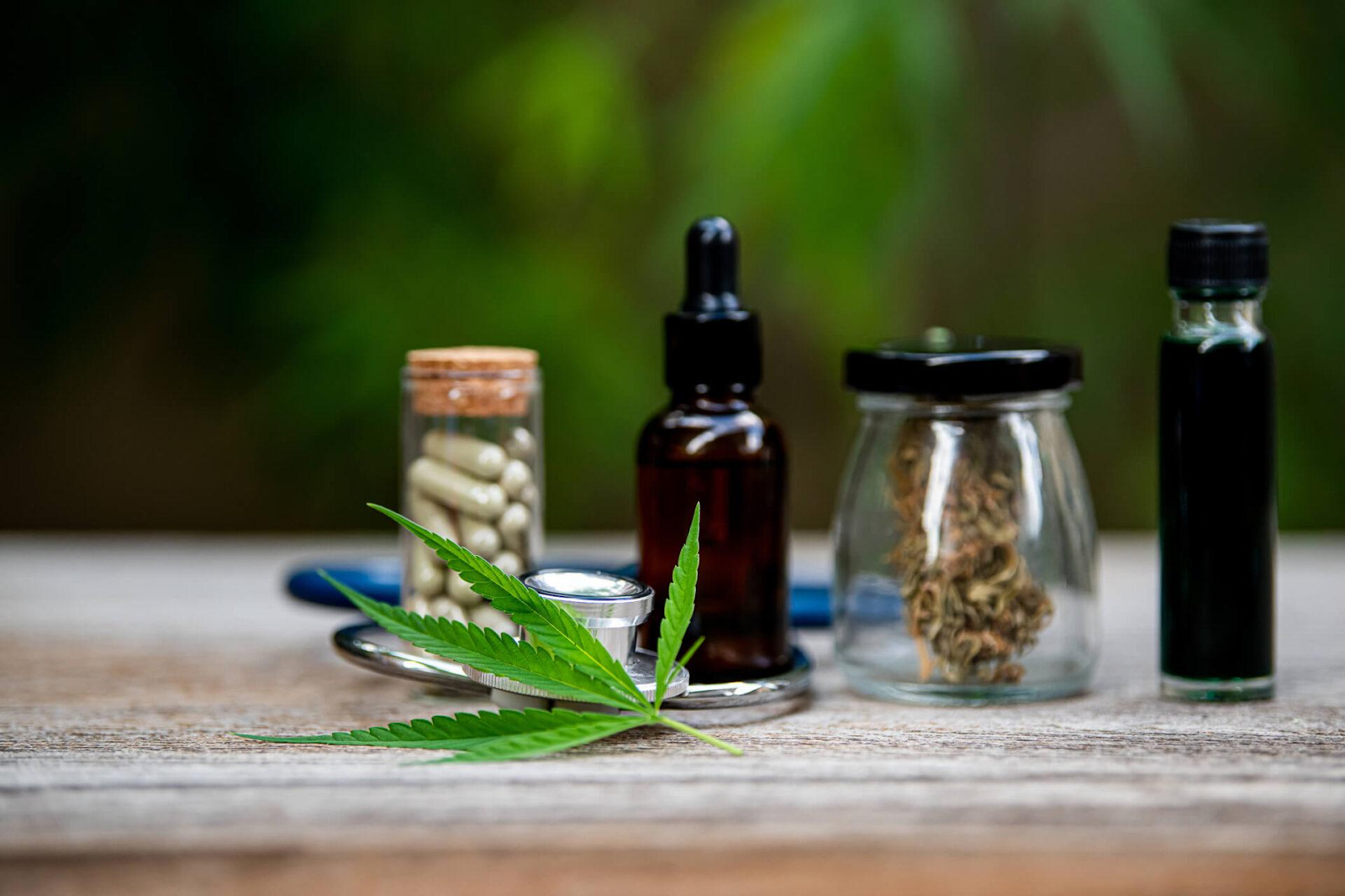 Cannabis leaf with various consumption methods including oil tinctures, dried flower, capsules, and vape cartridges