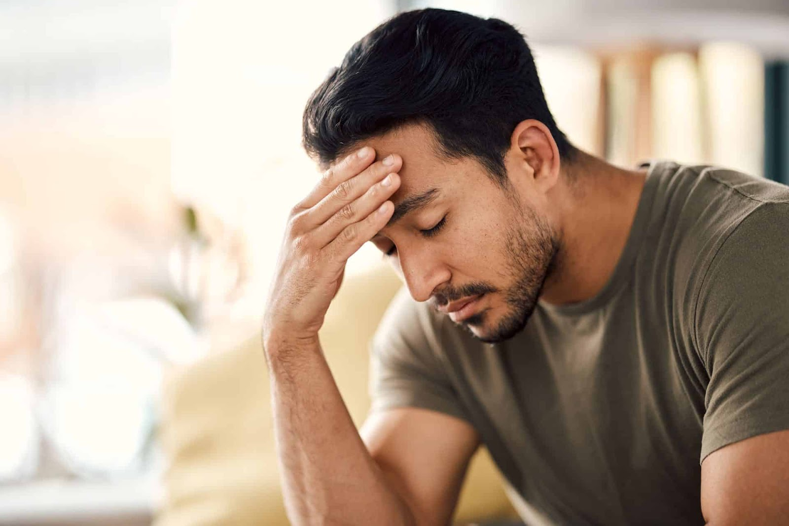 Man holding his forehead in a calm indoor setting, illustrating stress and anxiety relief